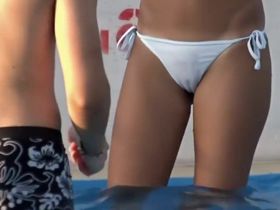 Худенькая тинка в бикини плескается в бассейне и светит через мокрую ткань щелью